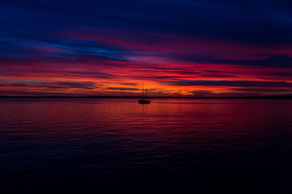 Free Image of Silhouette boat at tranquil sunset over calm ocean. 