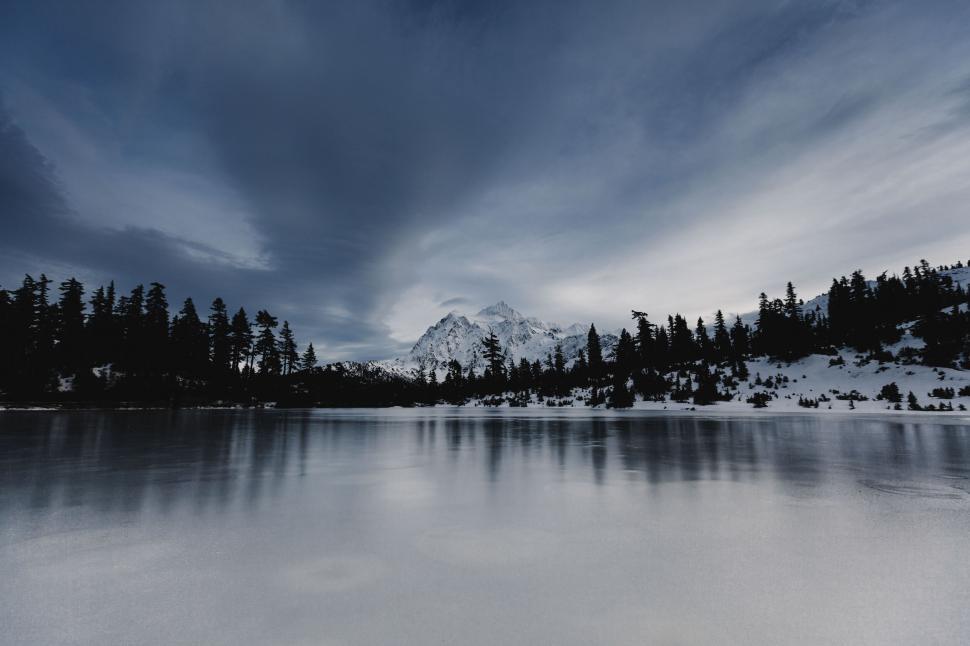 Free Image of Snow-capped mountains reflected in a calm icy lake. 