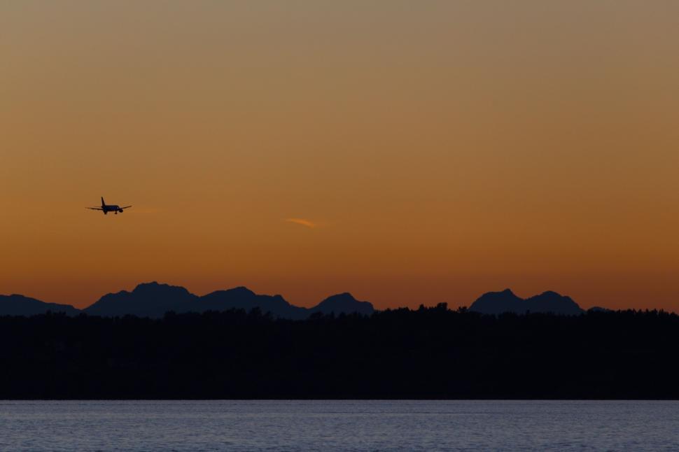 Free Image of Airplane flying over mountains during a sunset. 