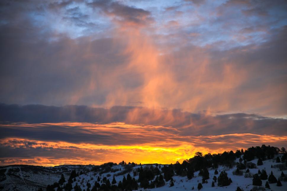 Free Image of Vibrant sunset over a snowy and hilly landscape 