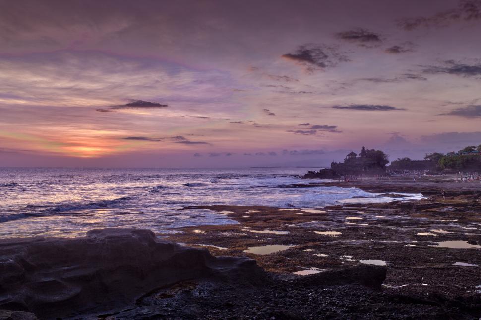 Free Image of Dramatic sunset over rocky coastline serene ocean view 