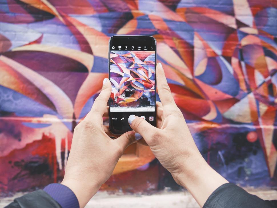 Free Image of Hands photographing colorful graffiti with smartphone, vivid. 