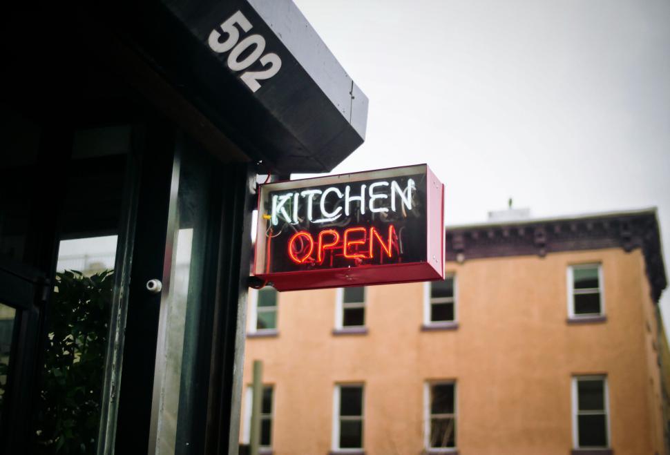 Free Image of Neon sign on building reads Kitchen Open bright colors 