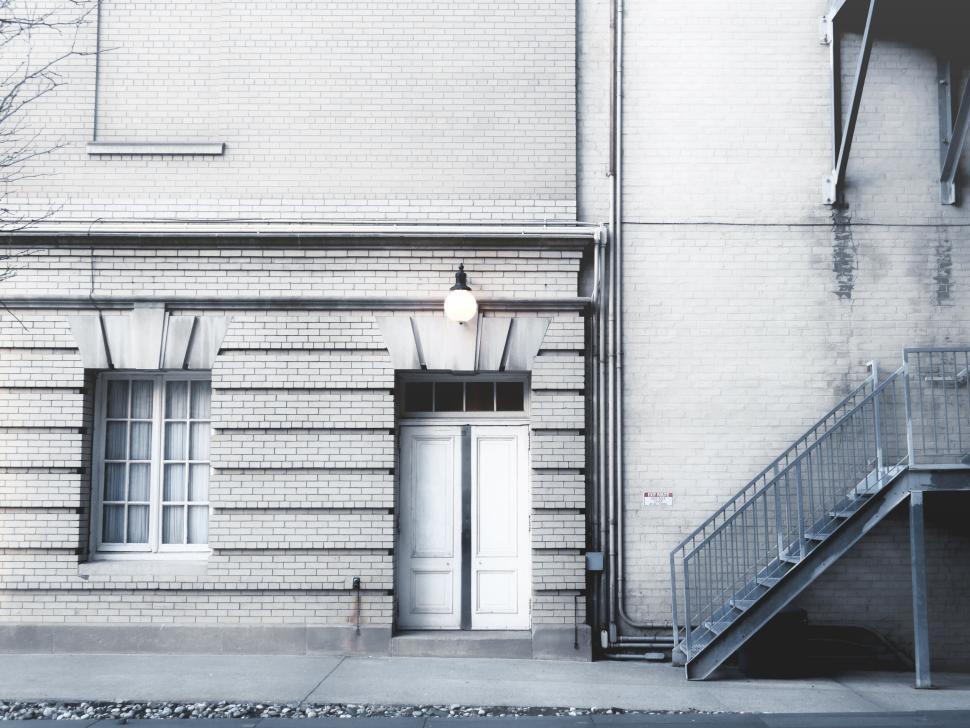 Free Image of Closed white door on side of light brick building 