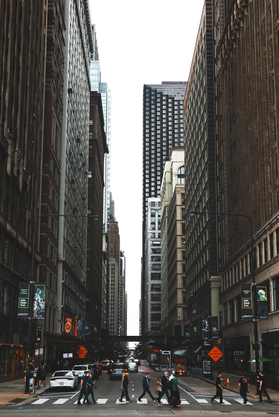 Free Image of Urban street scene with tall buildings and pedestrians crossing. 