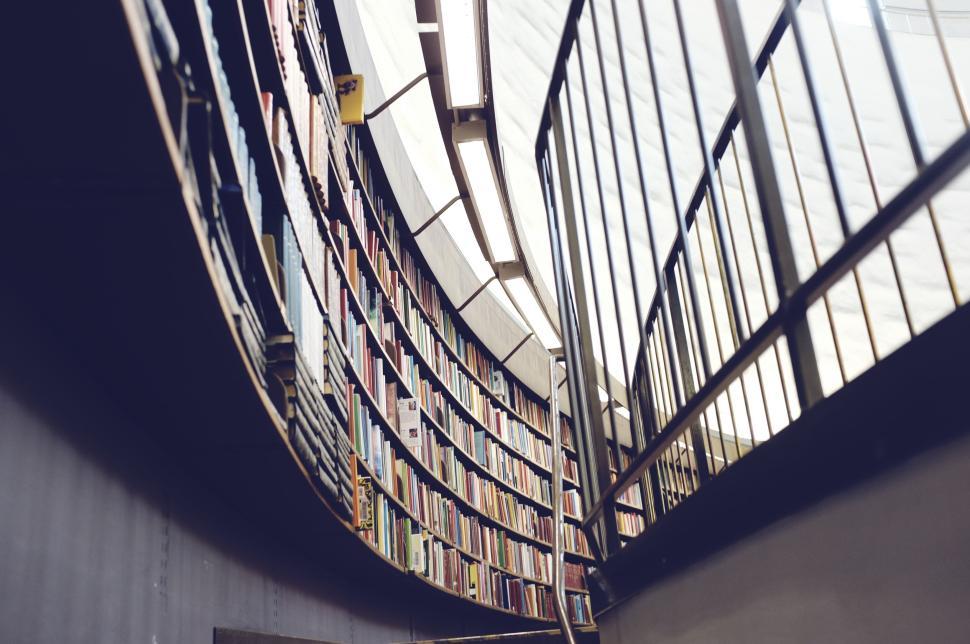 Free Image of Curved library shelving with rows of books and railings. 