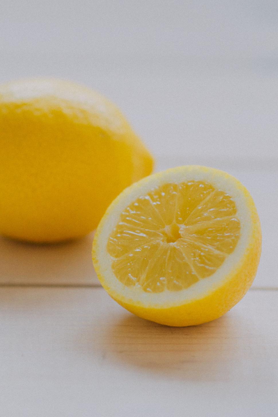 Free Image of Whole lemon and half-cut lemon on a white surface. 
