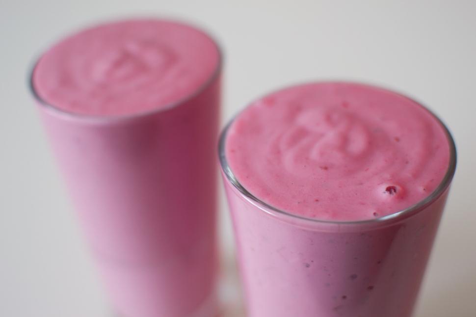 Free Image of Two glasses of pink smoothie placed on a white background. 