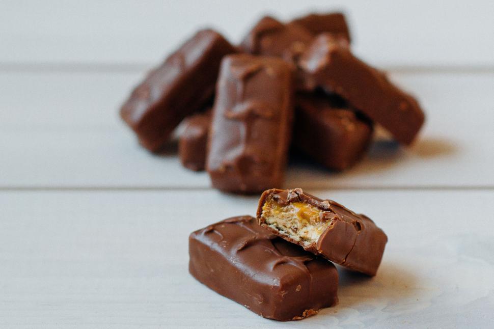 Free Image of Stacked chocolate bars on a table, one partially eaten. 