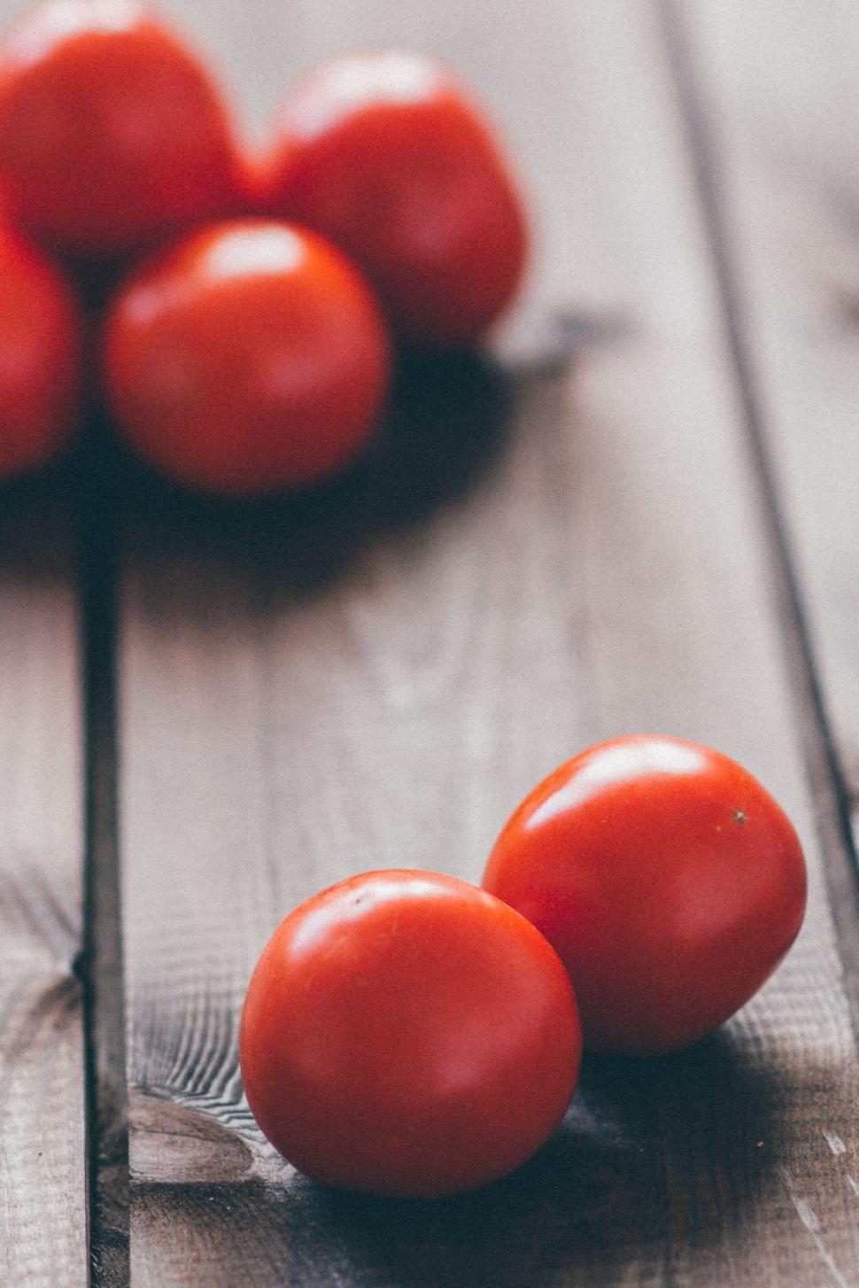Free Image of Several fresh tomatoes on a wooden table, seasonal produce. 