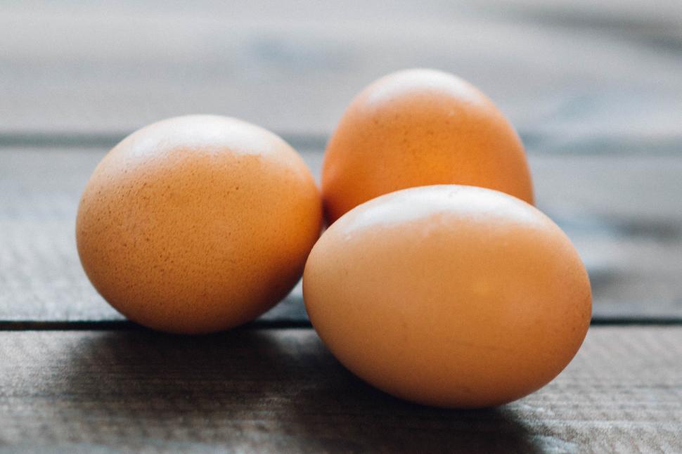 Free Image of Three fresh brown eggs on wooden surface close-up 