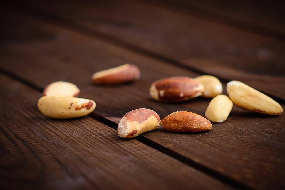 Free Image of Close-up of Brazil nuts scattered on wooden surface 