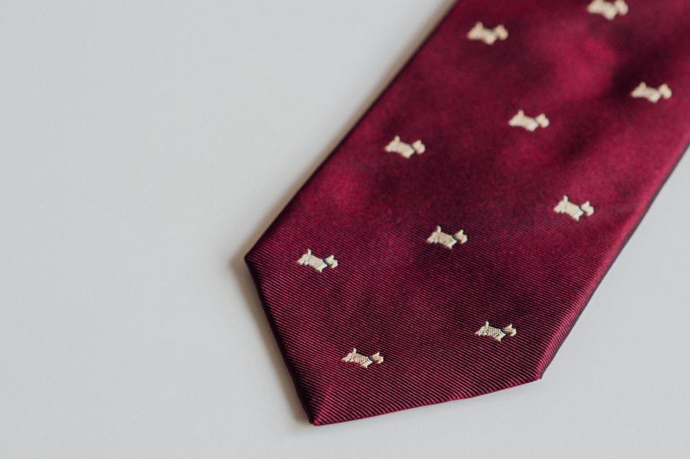 Free Image of Dark red necktie with dog patterns on white background 