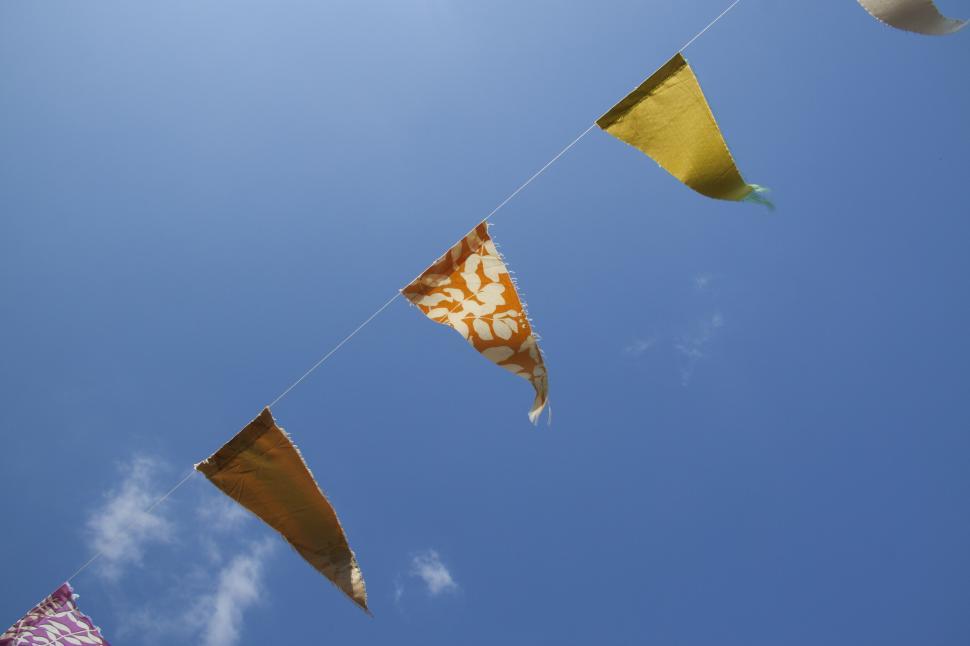 Free Image of Colorful flags against a clear, bright blue sky. 