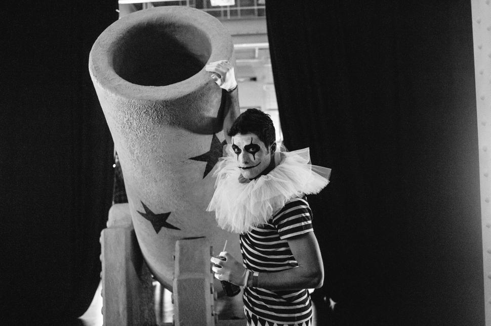 Free Image of Clown in costume next to giant cannon backstage at circus 