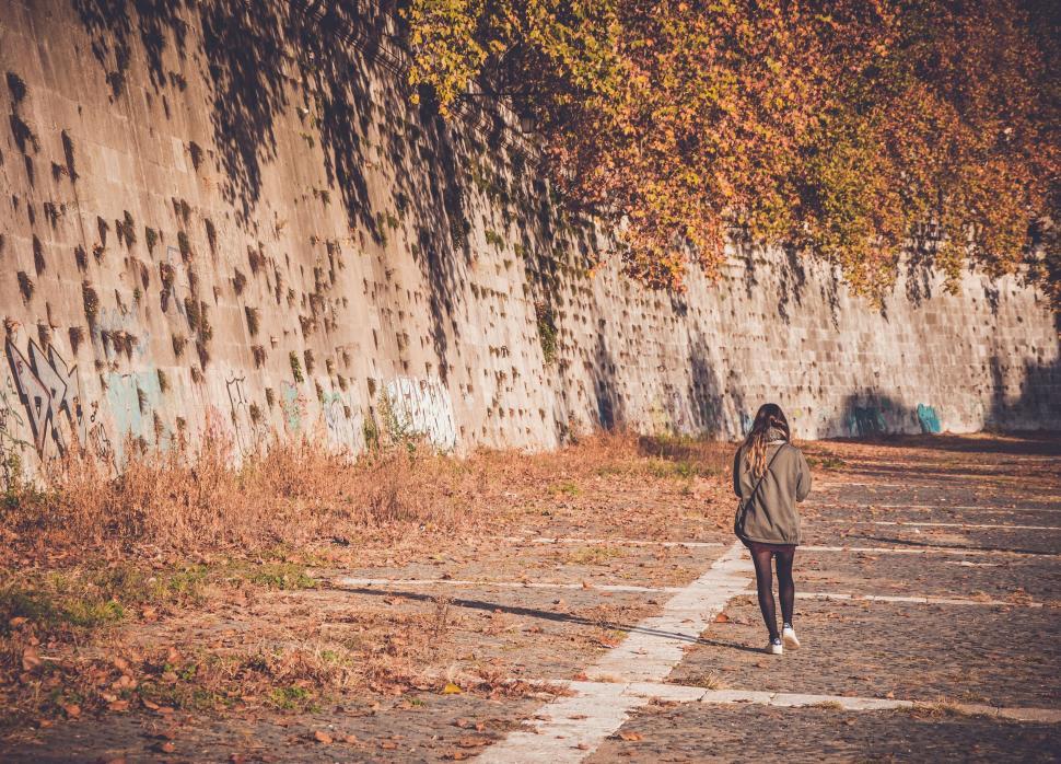 Free Image of Woman walking alone near wall with graffiti in autumn 