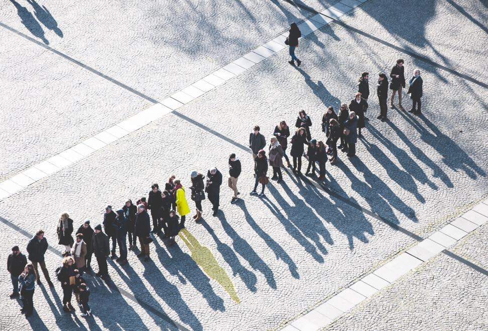 Free Image of People in a line casting long shadows on pavement area 