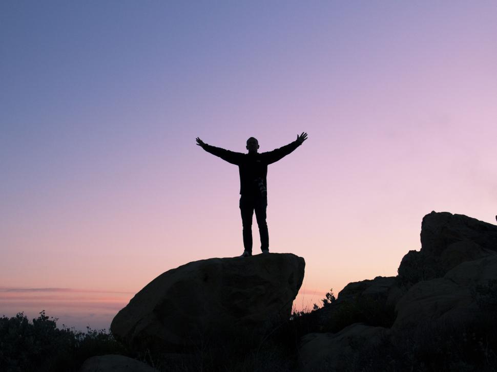 Free Image of Silhouette of person standing on rock at twilight 