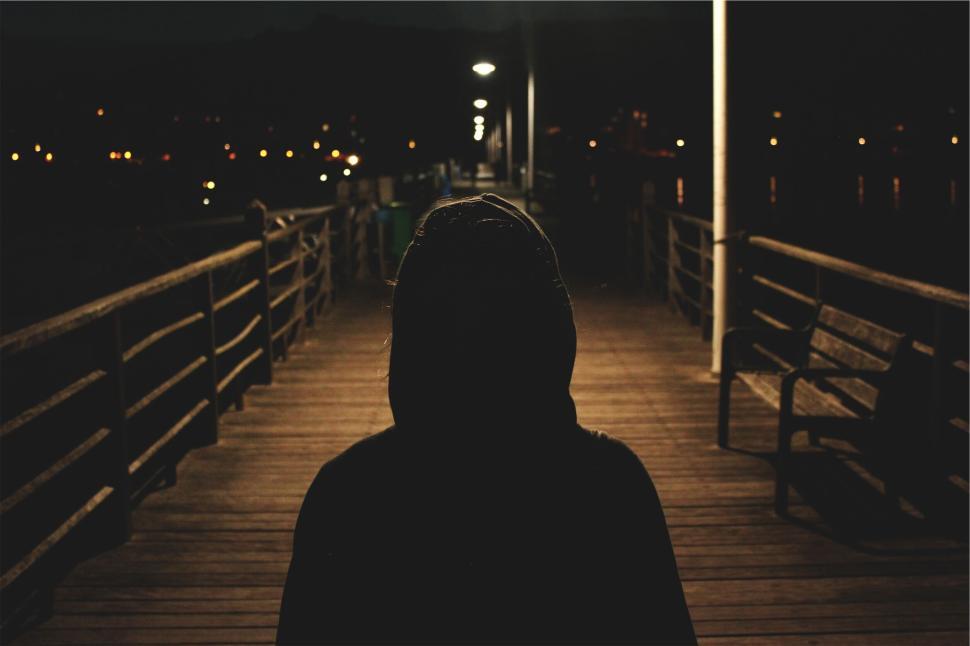 Free Image of Silhouette of hooded person walking on a dark pier 