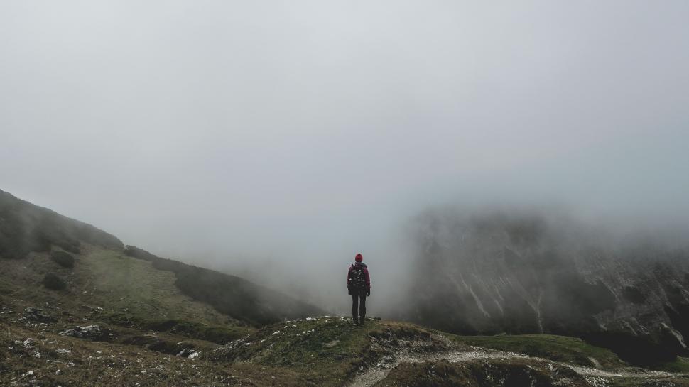 Free Image of Lone hiker stands amidst a foggy mountainous landscape 