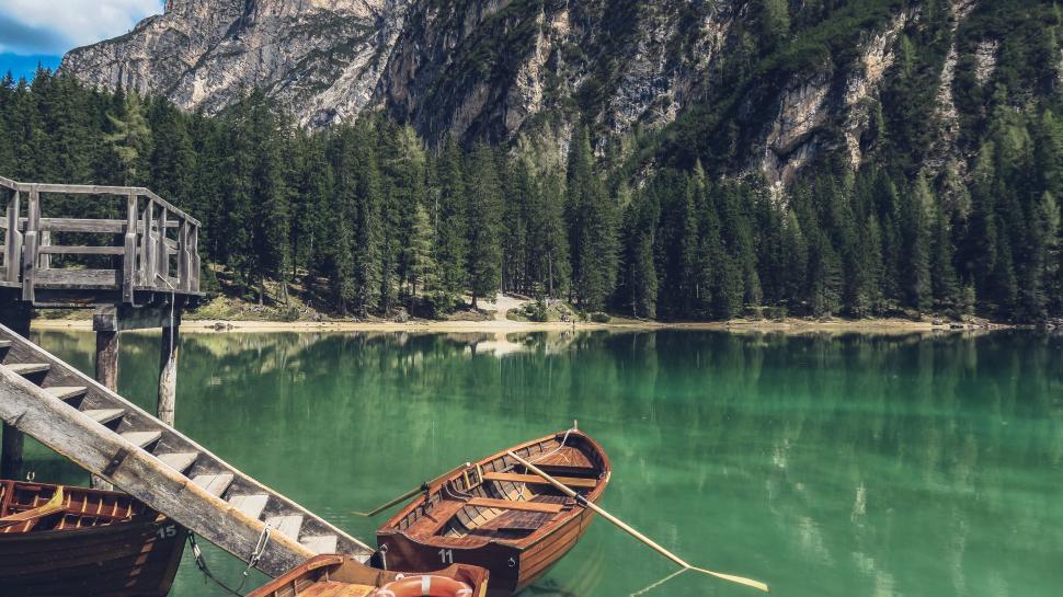 Free Image of Wooden boats docked at lake with forest and mountains 