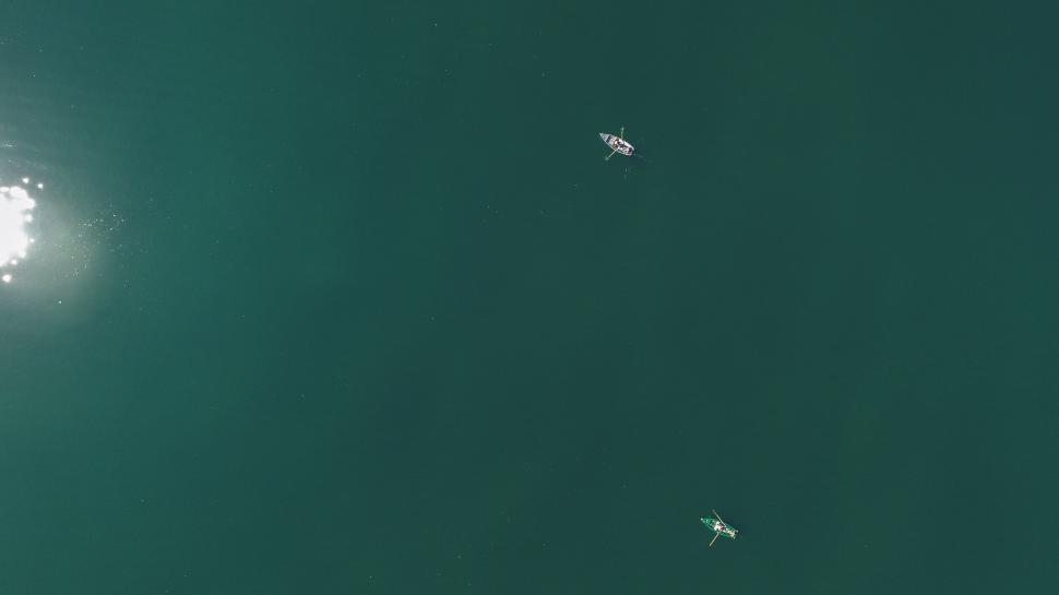 Free Image of Two kayakers paddling on calm emerald green waters 
