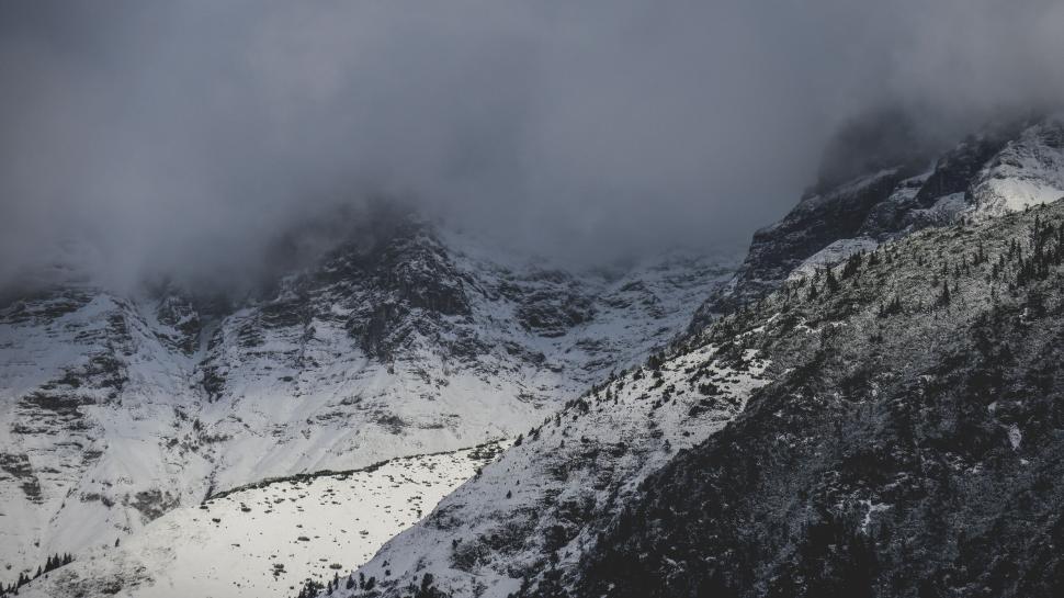 Free Image of Snow-covered mountain peaks partially shrouded in mist 