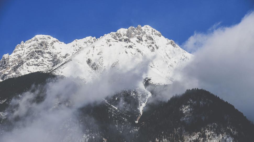 Free Image of Snow-capped mountain under bright blue sky with clouds 
