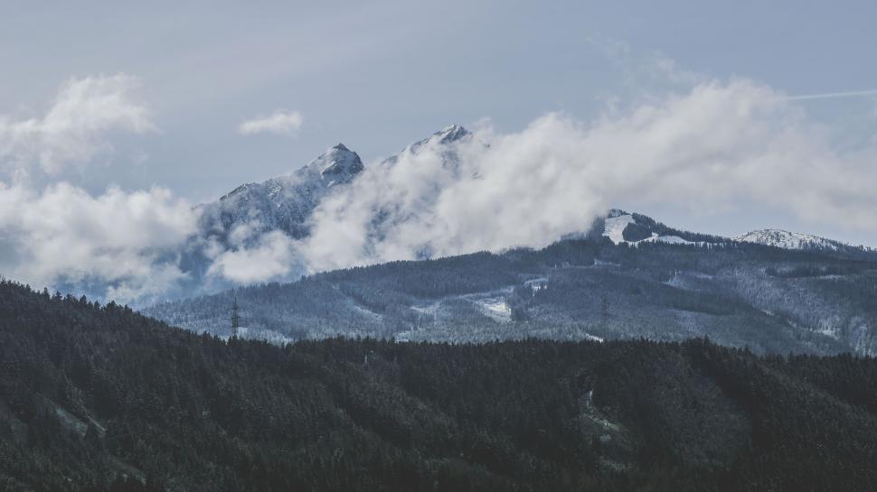 Free Image of Snow-capped mountain peaks partly covered by clouds. 