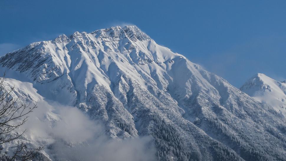 Free Image of Monumental snow-covered mountain with blue sky above. 