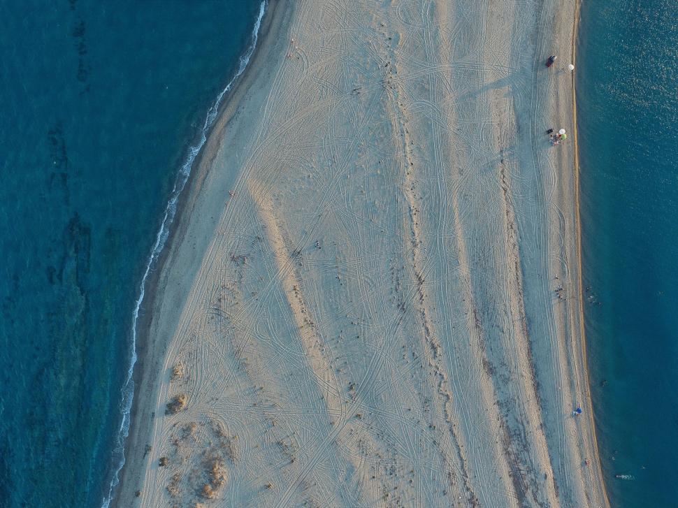 Free Image of Aerial view of sandy beach with tracks and ocean waves. 