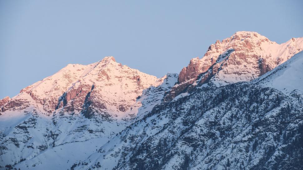 Free Image of Distant snow-covered mountain peaks under a blue sky. 