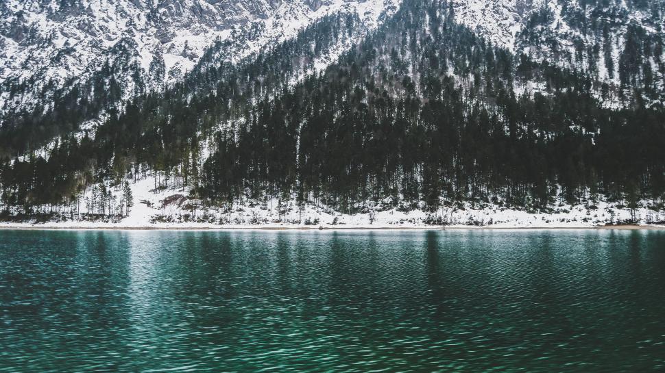 Free Image of Snow-covered mountain viewed across a calm teal lake. 