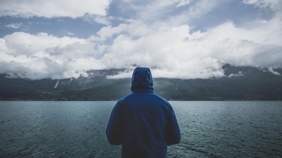 Free Image of Person in blue jacket facing calm scenic lake view. 