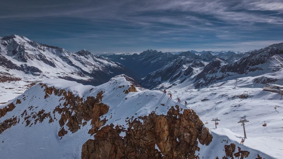 Free Image of Snow-covered mountain range with skiers on slopes 