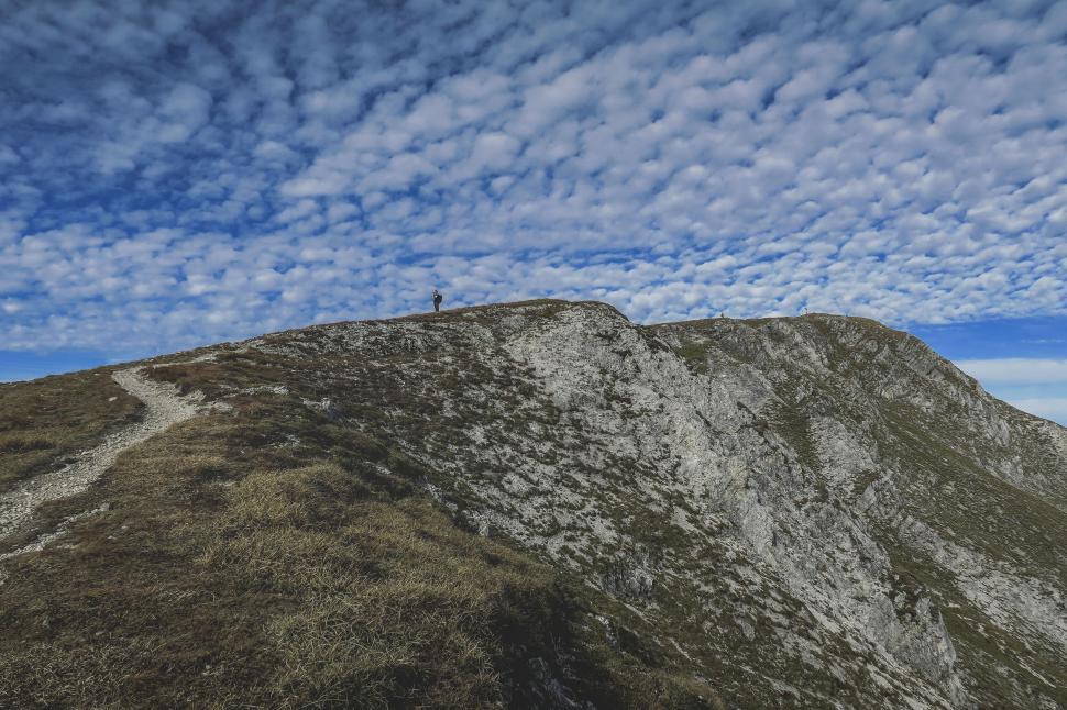 Free Image of Hiker on mountain top with clear blue sky background 