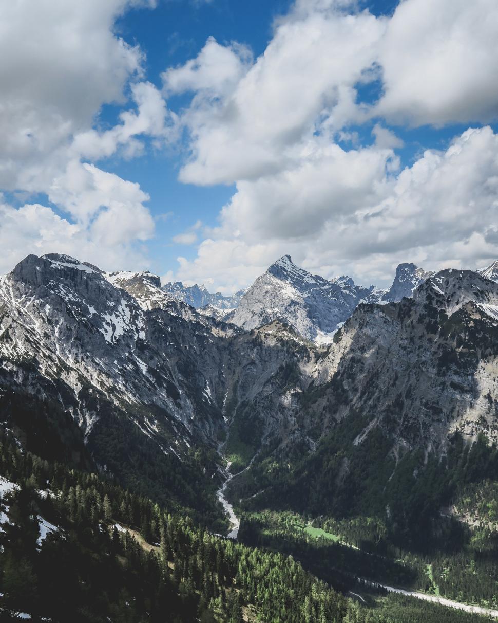 Free Image of Mountain valley with forest and rocky peaks under clouds 