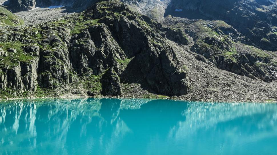 Free Image of Turquoise lake amidst rocky mountains under clear sky. 