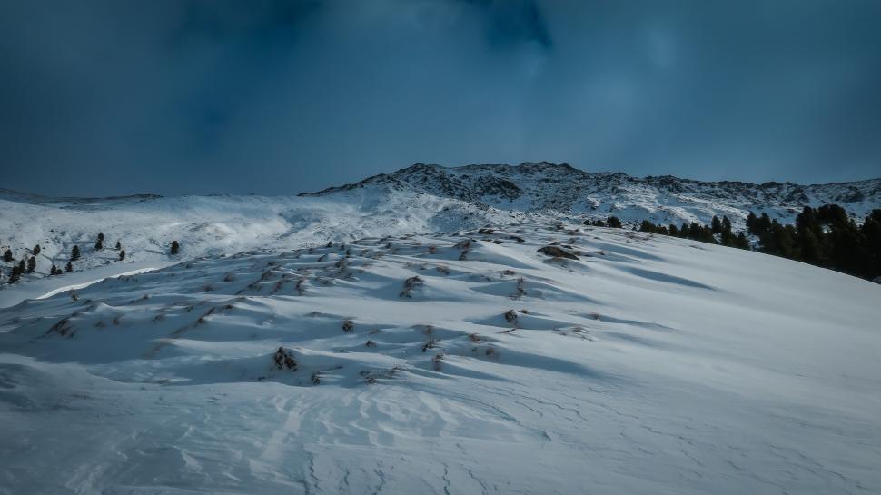 Free Image of Snow-covered slope under a cloudy winter sky, tranquil. 