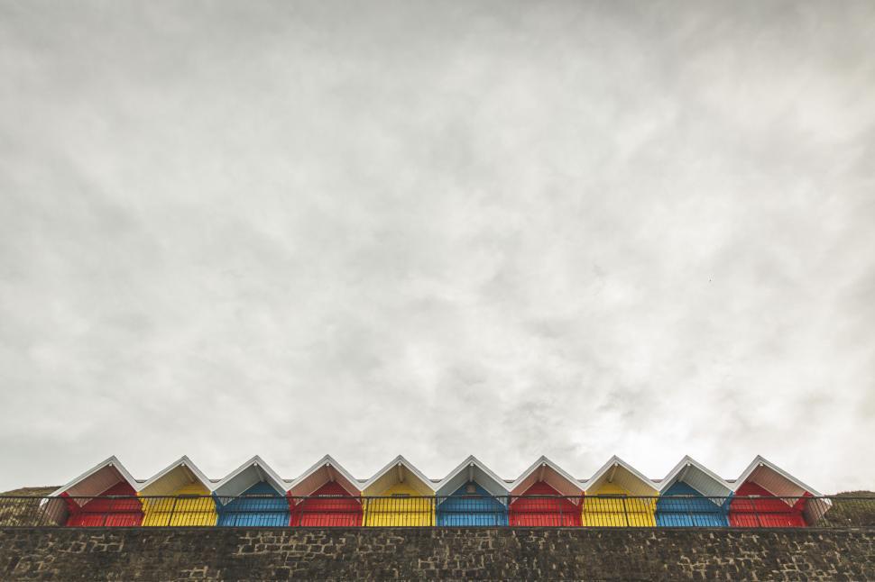 Free Image of Colorful beach huts lined up under an overcast sky 