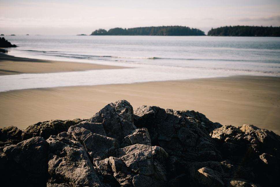 Free Image of Rocky beach with calm ocean waters and distant isles 