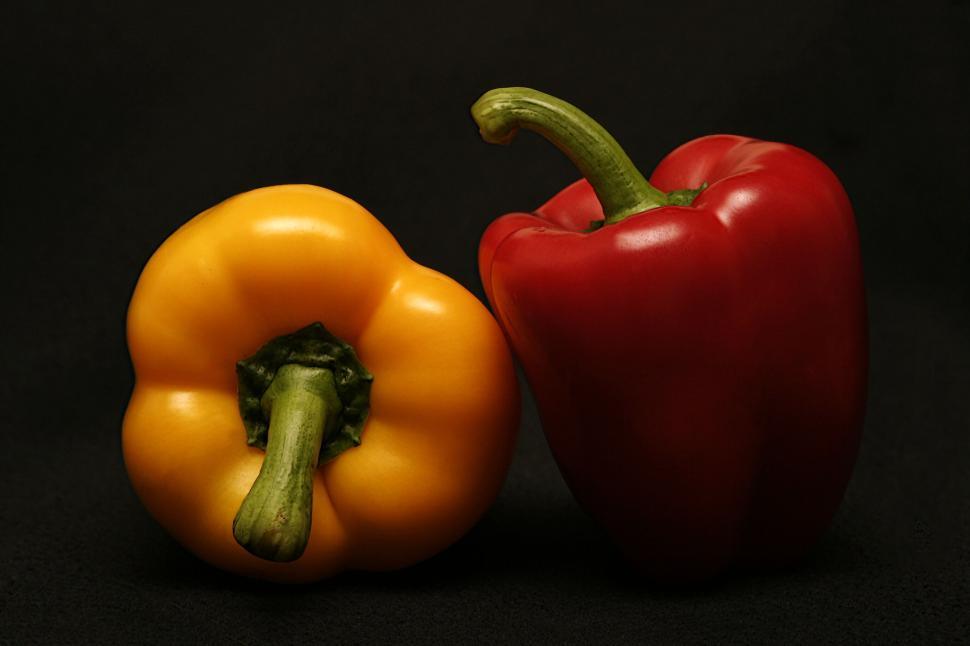 Free Image of Yellow and Red Bell Peppers Against Black Background 