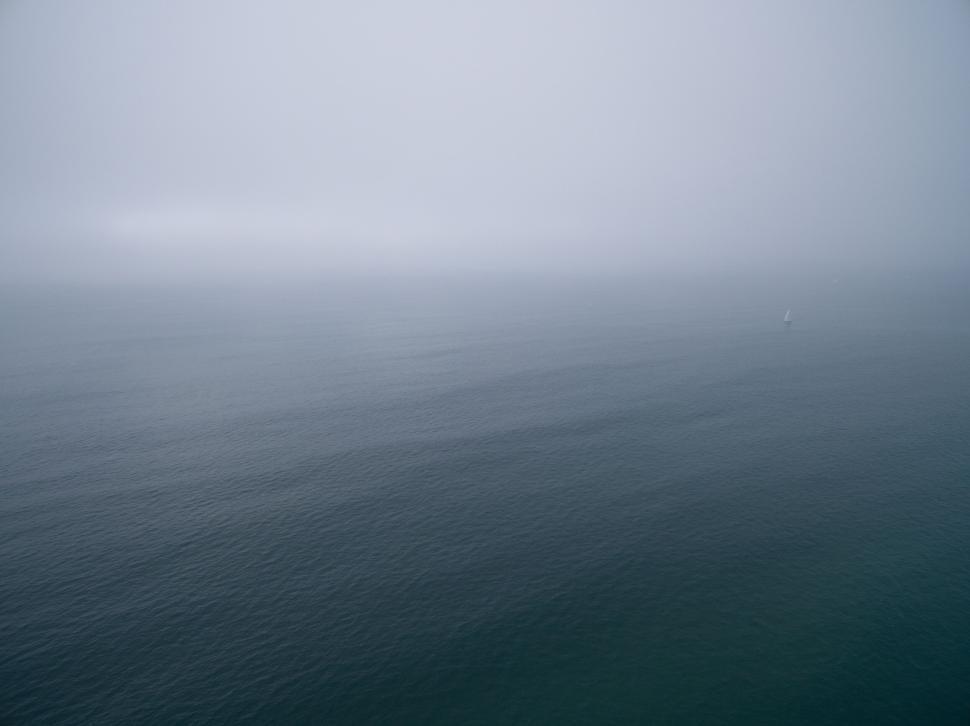Free Image of A foggy and calm ocean with distant horizon visible. 