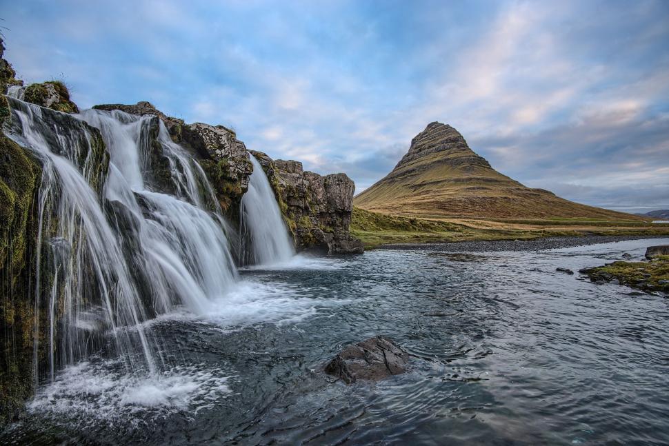 Free Image of Waterfall with mountain in background under cloudy sky 