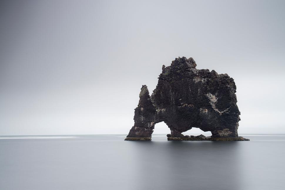Free Image of Rock formation in calm sea under overcast gray skies 