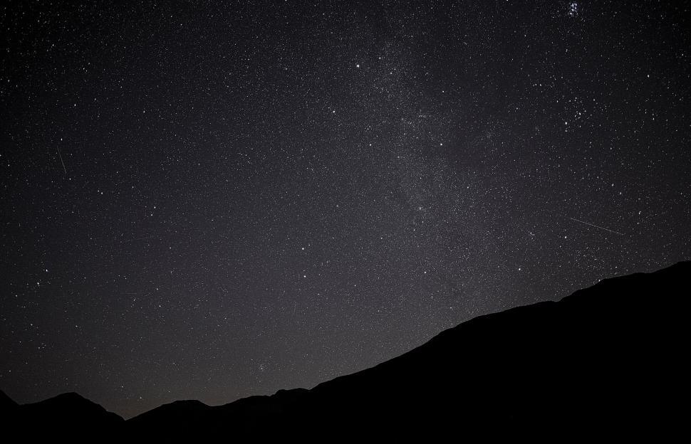 Free Image of Starry night sky over silhouetted mountainous terrain 