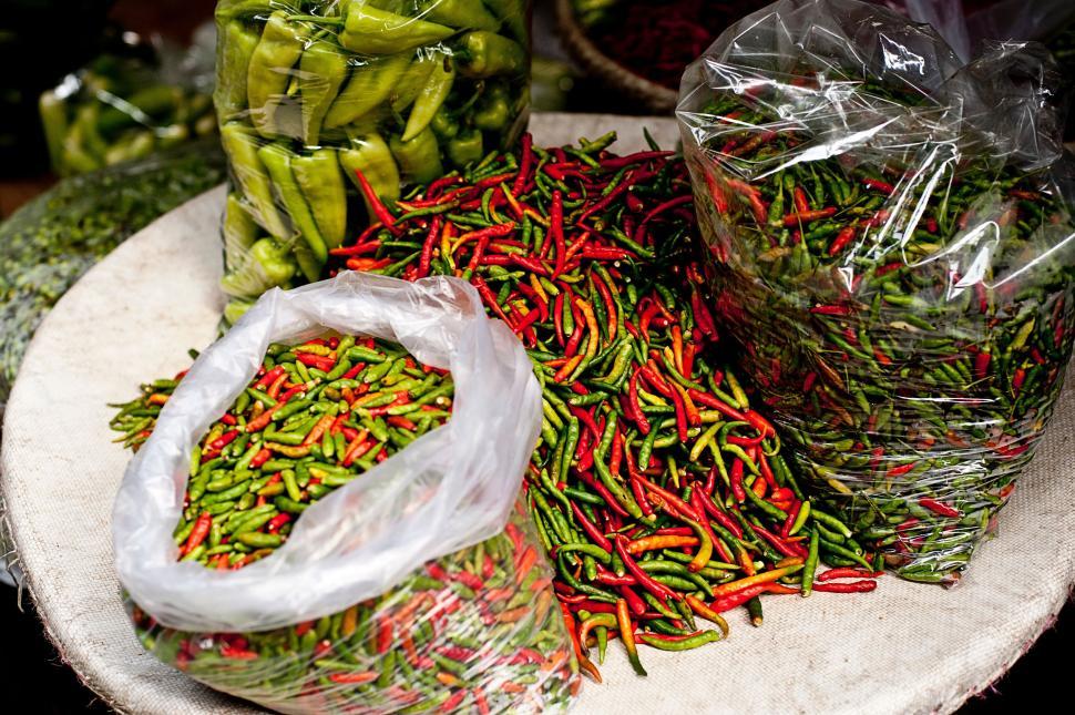 Free Image of Bags of green and red chili peppers at a market 