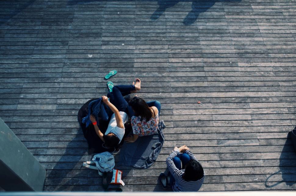 Free Image of Group of friends sitting together on wooden deck outside 