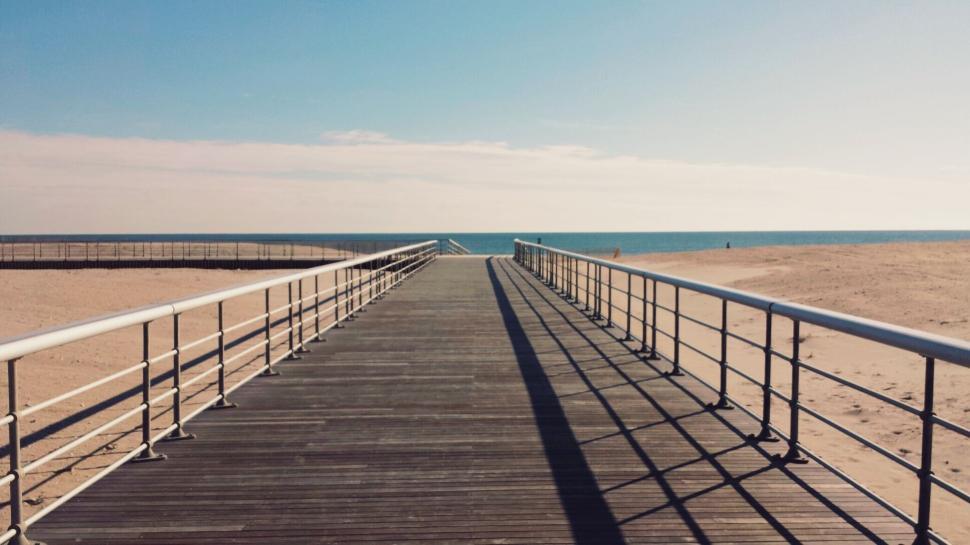 Free Image of Boardwalk leading to the beach with clear blue skies 