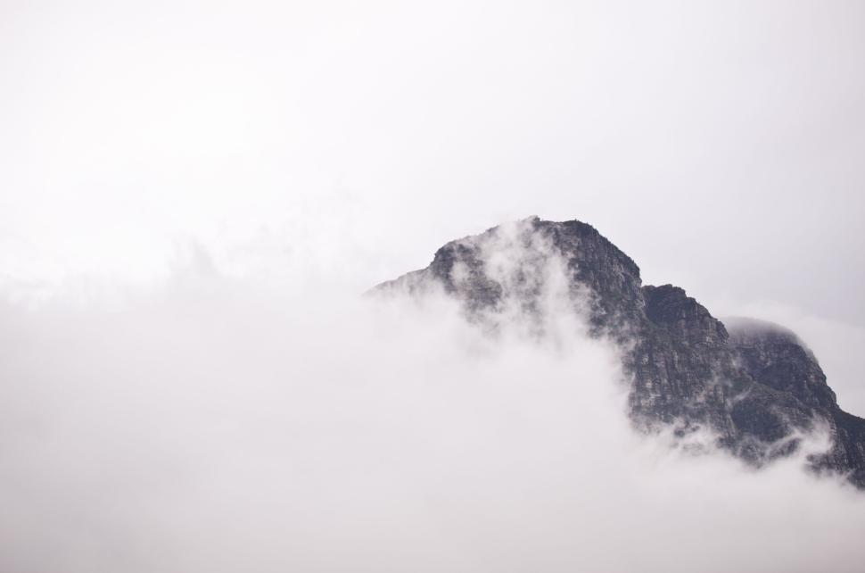Free Image of Mountain partially obscured by thick, white clouds. 